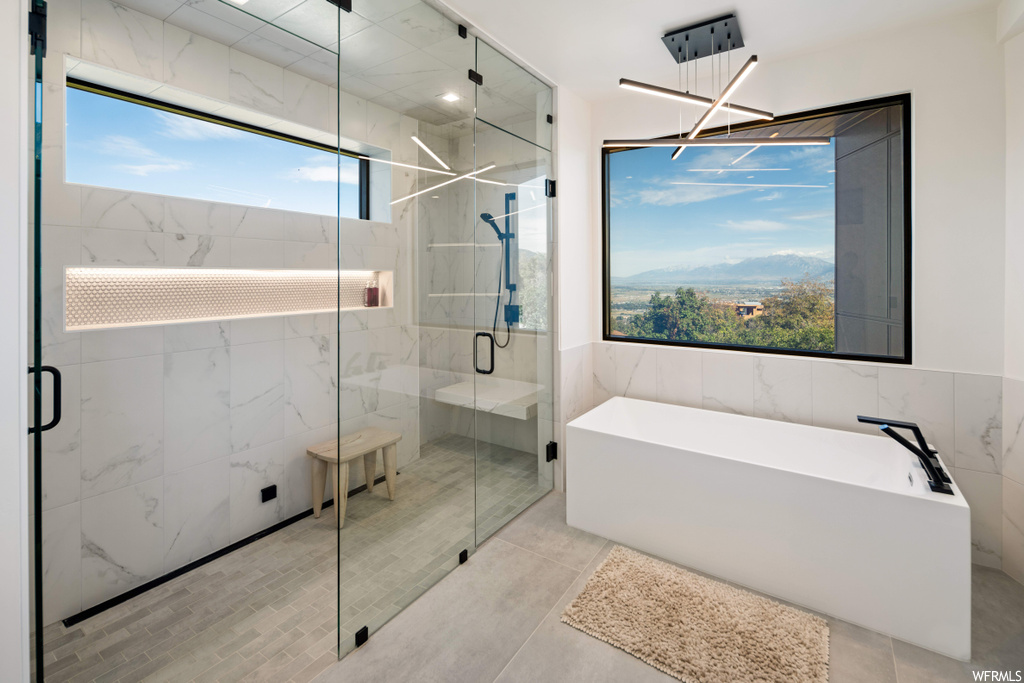 Bathroom featuring separate shower and tub, a wealth of natural light, and tile flooring