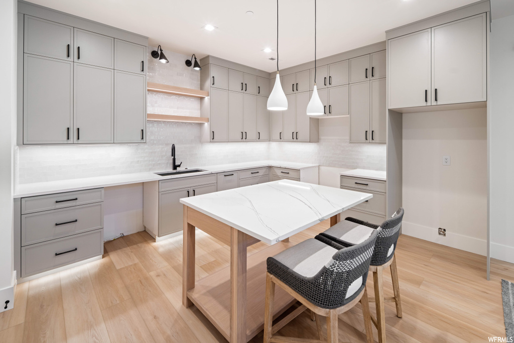 Kitchen with sink, decorative light fixtures, backsplash, and light hardwood / wood-style floors
