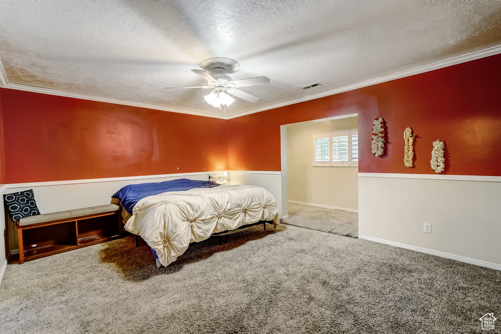 Carpeted bedroom with ornamental molding, a textured ceiling, and ceiling fan