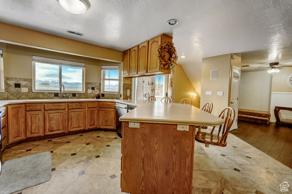 Kitchen with light tile floors, ceiling fan, tasteful backsplash, dishwasher, and sink