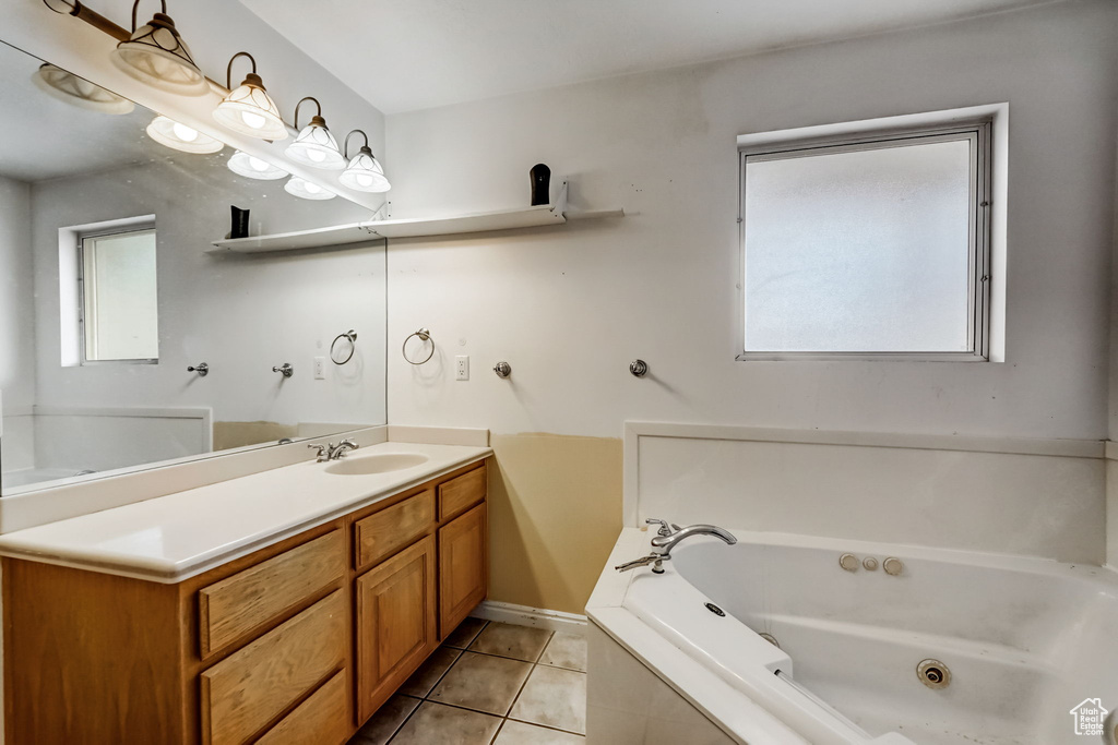 Bathroom featuring tiled tub, vanity, tile floors, and plenty of natural light