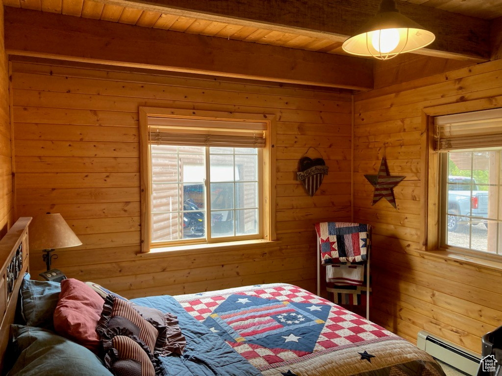 Bedroom with beam ceiling, wooden walls, baseboard heating, and wood ceiling