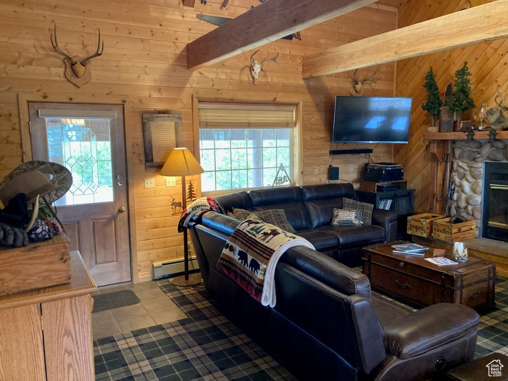 Tiled living room with a baseboard heating unit, wooden walls, beam ceiling, and a fireplace