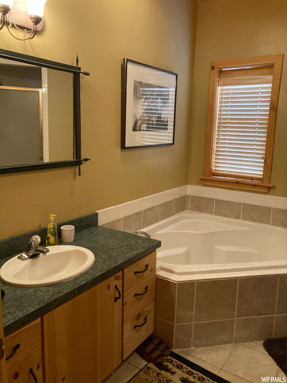 Bathroom featuring tiled bath, tile flooring, and large vanity
