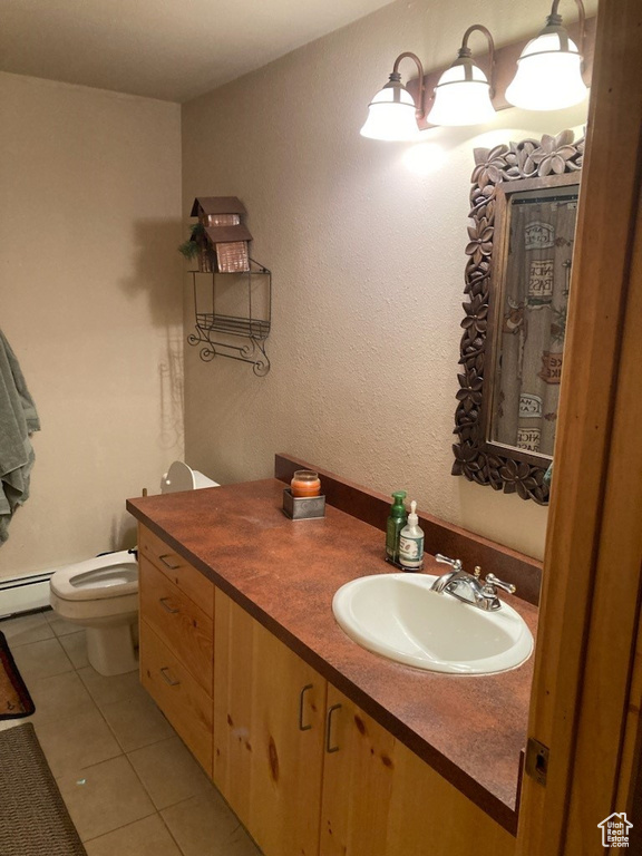 Bathroom with tile floors, a baseboard heating unit, toilet, and large vanity