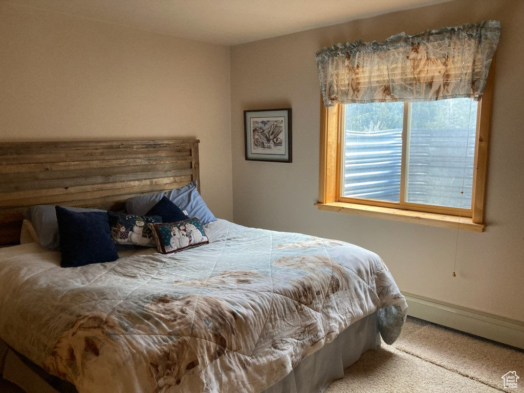 Carpeted bedroom with a baseboard heating unit