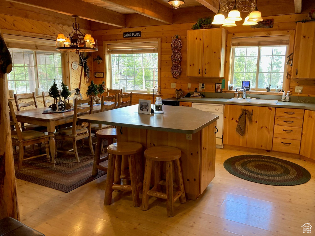 Kitchen featuring wooden walls, sink, light hardwood / wood-style floors, and white dishwasher