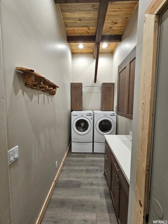 Clothes washing area featuring dark hardwood / wood-style flooring, washing machine and dryer, wooden ceiling, and cabinets