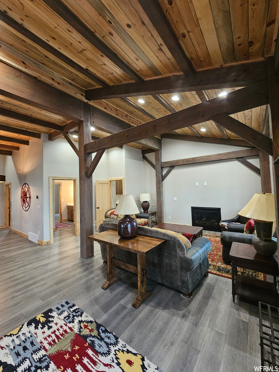 Living room with vaulted ceiling with beams, wood-type flooring, and wood ceiling