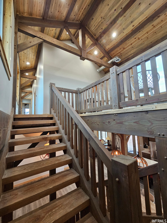 Stairway featuring a wealth of natural light, wood ceiling, bar area, and lofted ceiling with beams