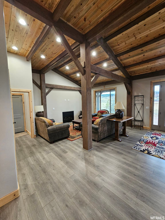 Living room featuring light wood-type flooring, vaulted ceiling with beams, and wooden ceiling