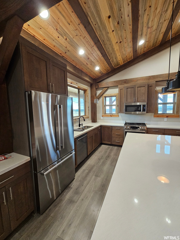 Kitchen with wood ceiling, hanging light fixtures, lofted ceiling with beams, light hardwood / wood-style floors, and stainless steel appliances
