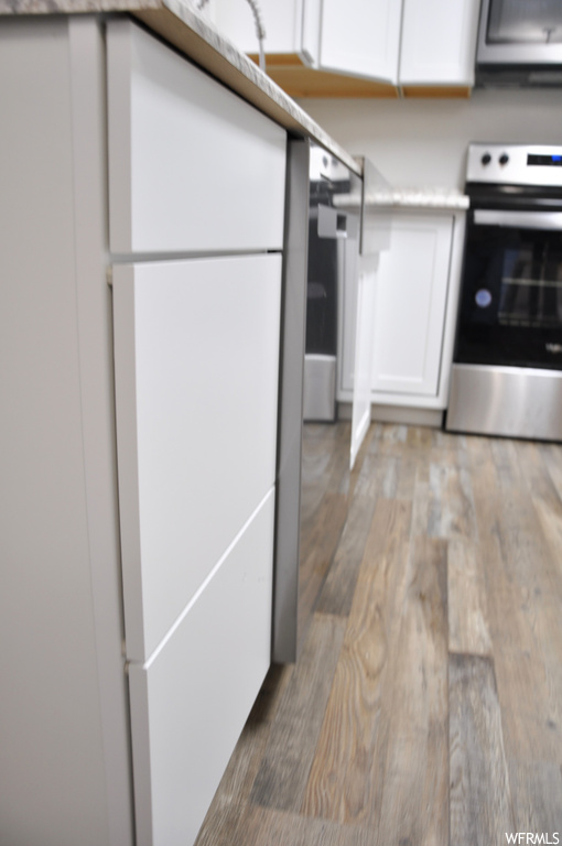 Kitchen with hardwood / wood-style flooring, range, and white cabinets