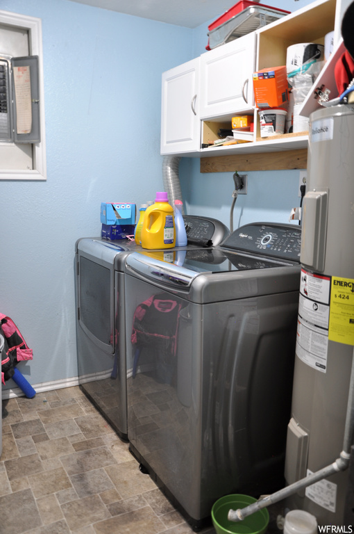 Clothes washing area with electric water heater, washing machine and clothes dryer, cabinets, and light tile floors