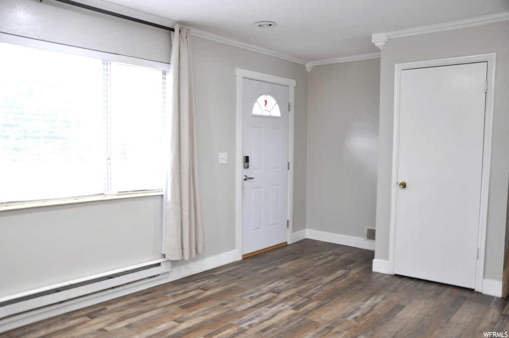 Foyer entrance with baseboard heating, crown molding, and dark wood-type flooring