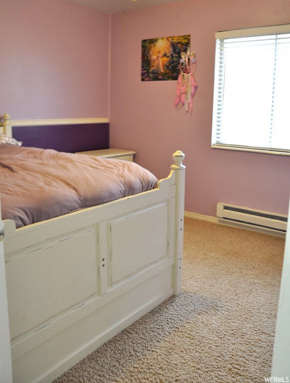 Unfurnished bedroom featuring baseboard heating and light colored carpet