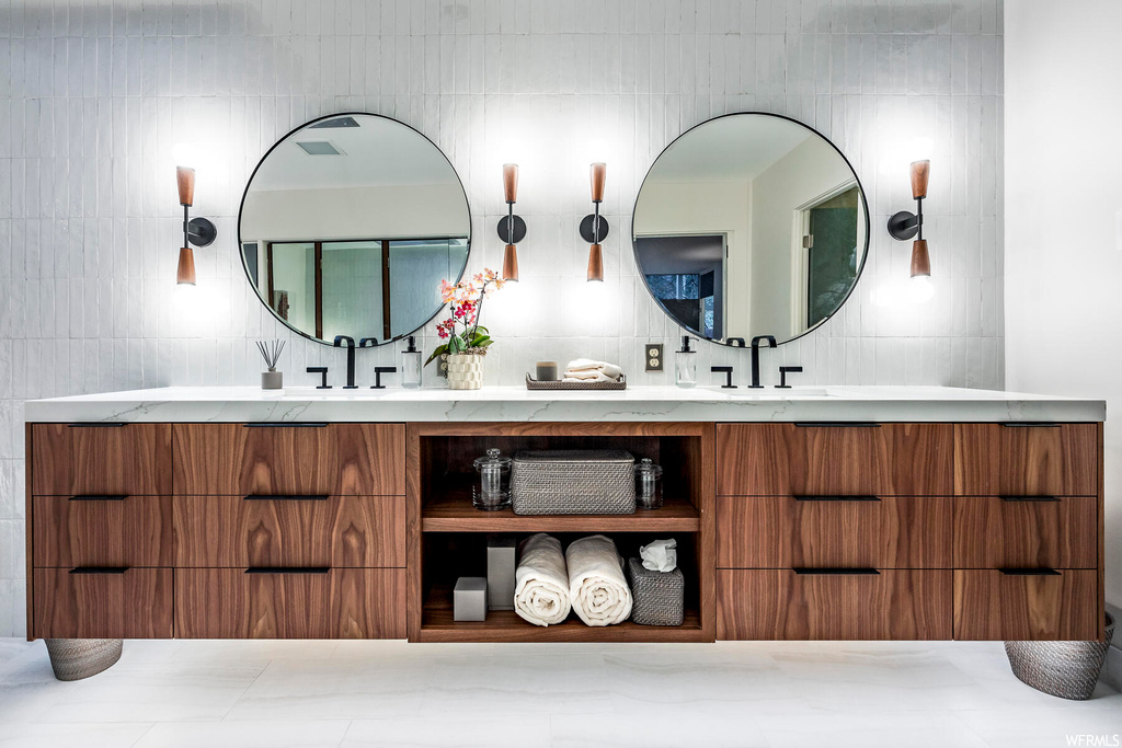 Bathroom featuring tasteful backsplash, double sink, tile walls, and oversized vanity