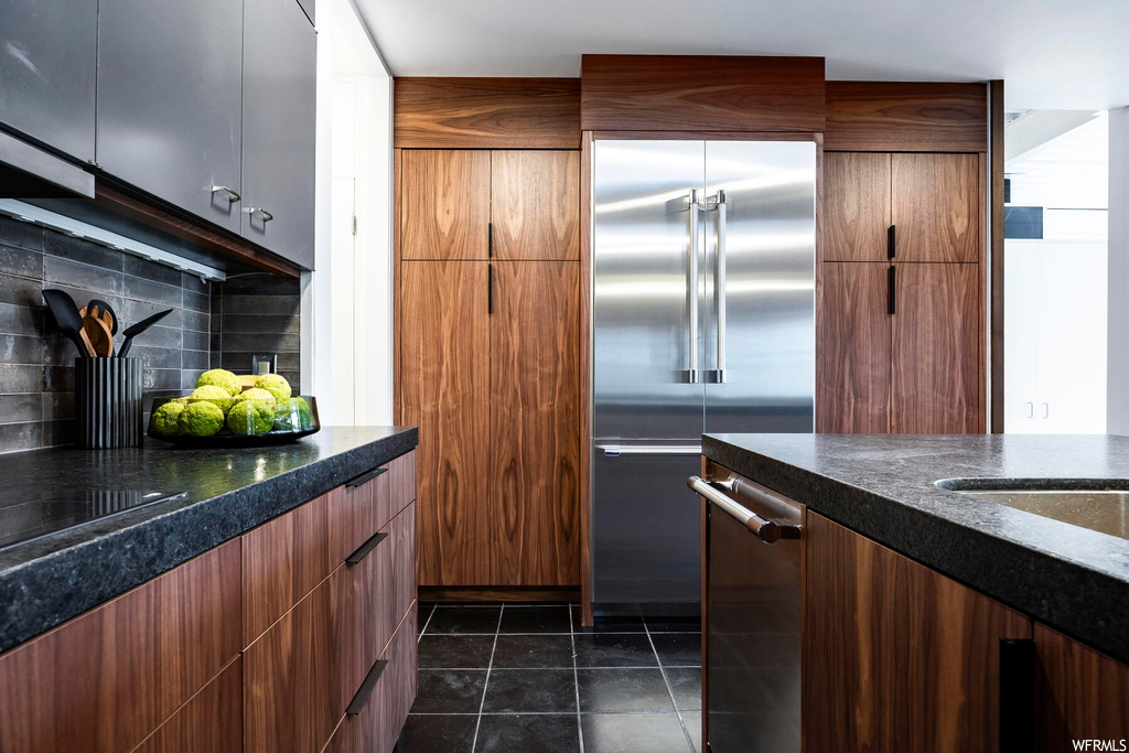 Kitchen featuring stainless steel appliances, dark tile flooring, and tasteful backsplash