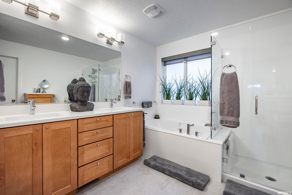 Bathroom featuring plus walk in shower, a textured ceiling, tile flooring, and double sink vanity