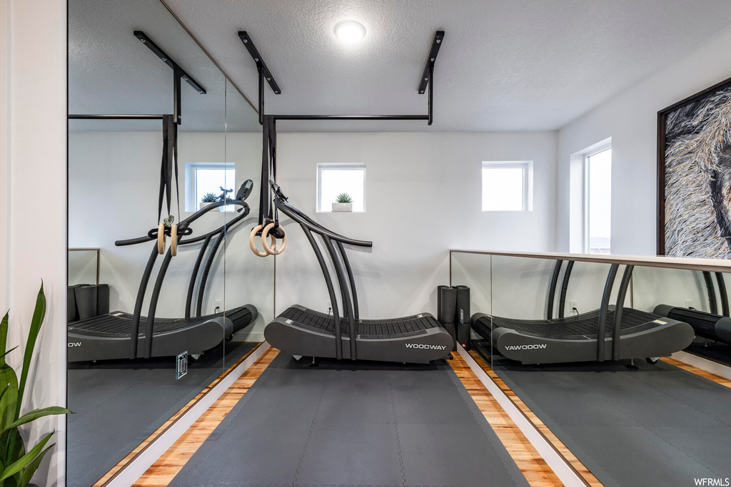 Workout area with hardwood / wood-style floors, a textured ceiling, and a wealth of natural light