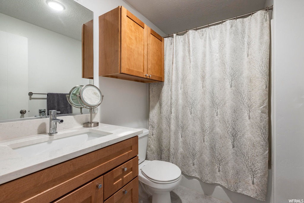 Bathroom featuring tile flooring, a textured ceiling, large vanity, and toilet