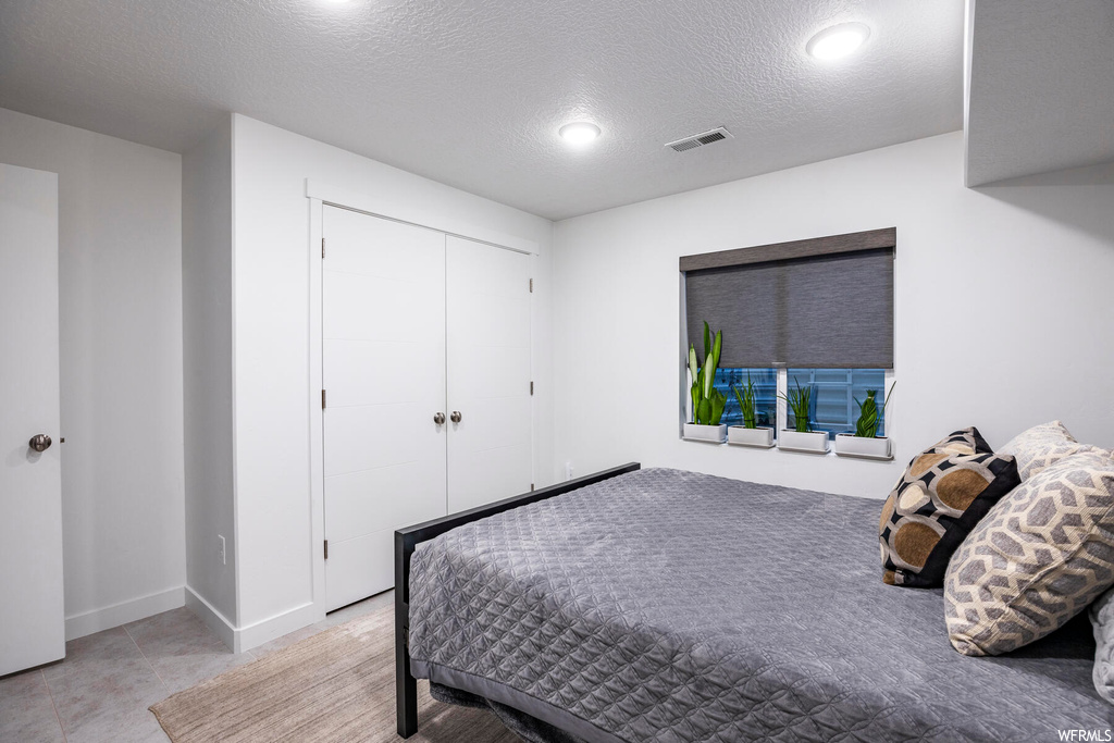 Bedroom with light tile floors, a closet, and a textured ceiling