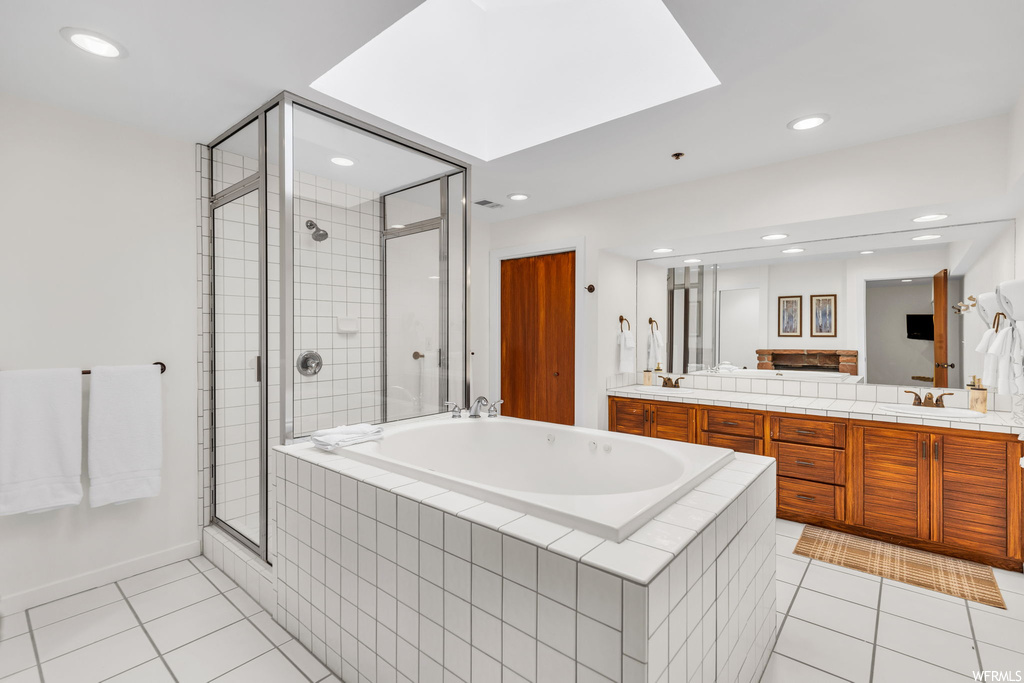 Bathroom featuring tile floors, dual bowl vanity, and shower with separate bathtub