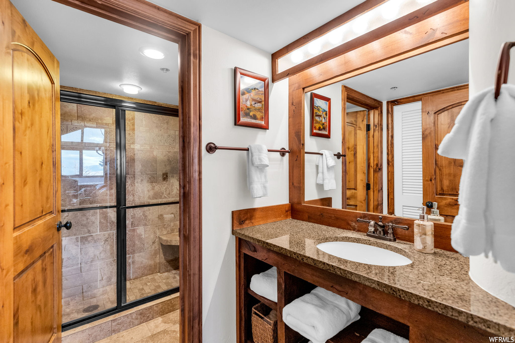 Bathroom featuring oversized vanity, tile flooring, and a shower with door