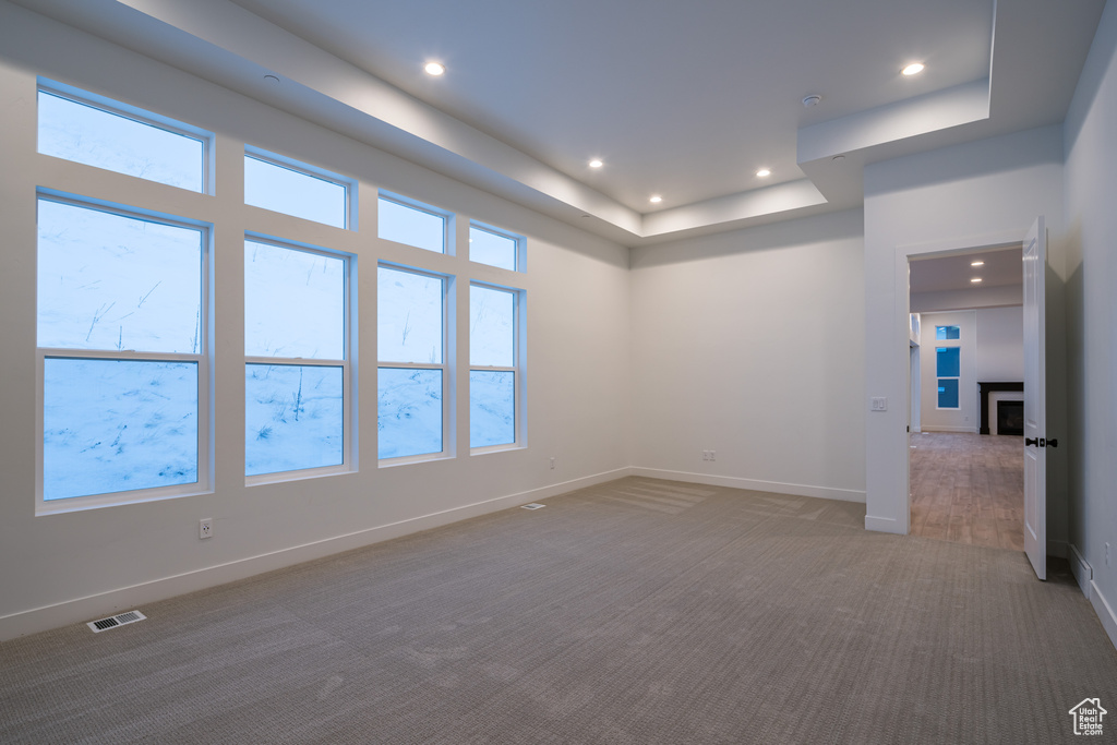 Unfurnished room with dark carpet, plenty of natural light, and a raised ceiling