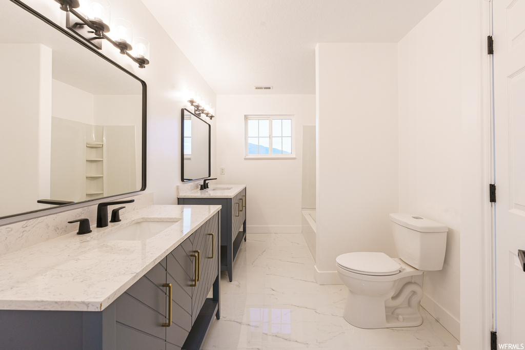 Bathroom with tile flooring, toilet, and double sink vanity