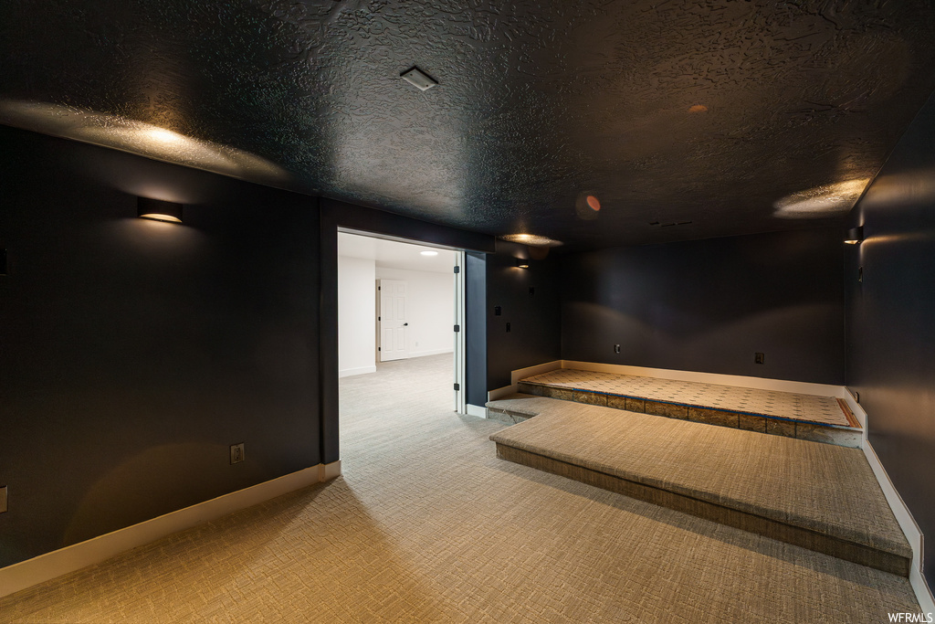 Home theater featuring a textured ceiling and light carpet