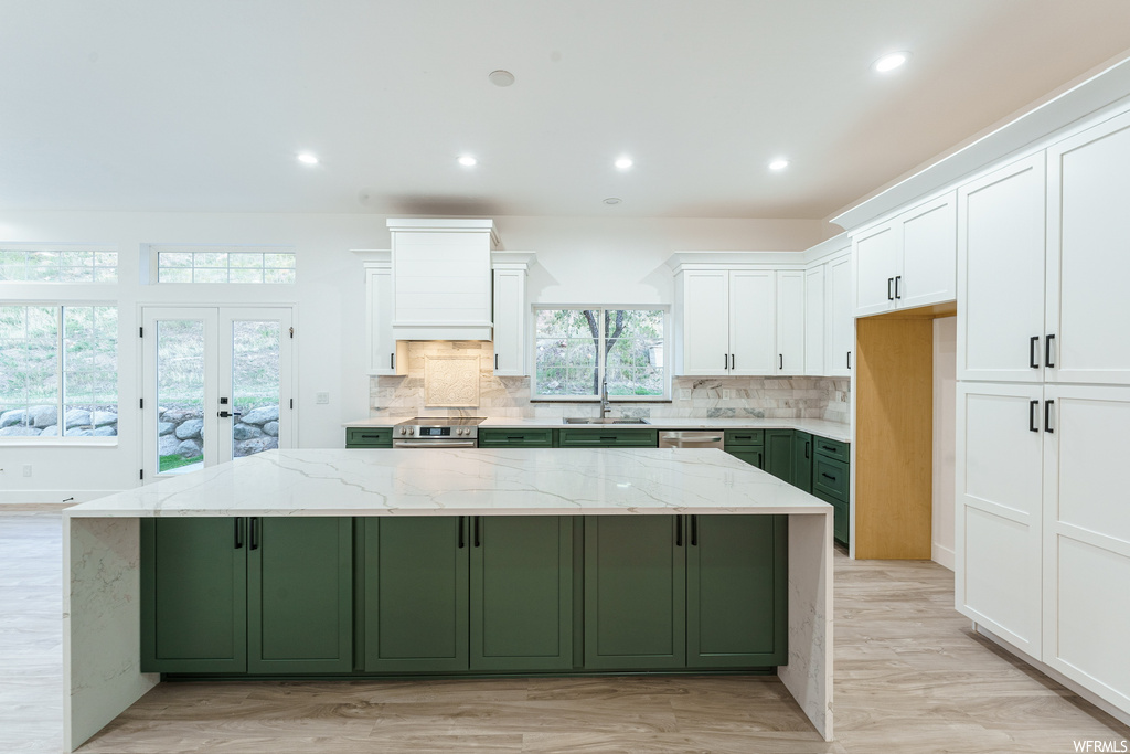 Kitchen featuring a center island, backsplash, white cabinetry, french doors, and green cabinetry