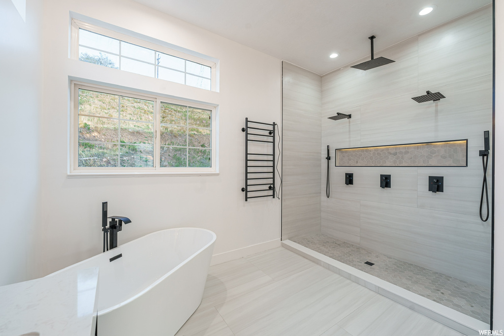 Bathroom with separate shower and tub, a wealth of natural light, radiator, and tile floors