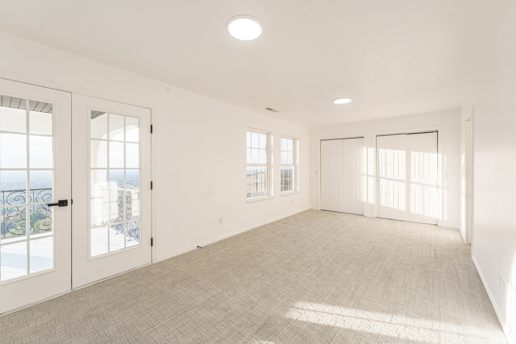 Unfurnished room featuring light colored carpet and french doors