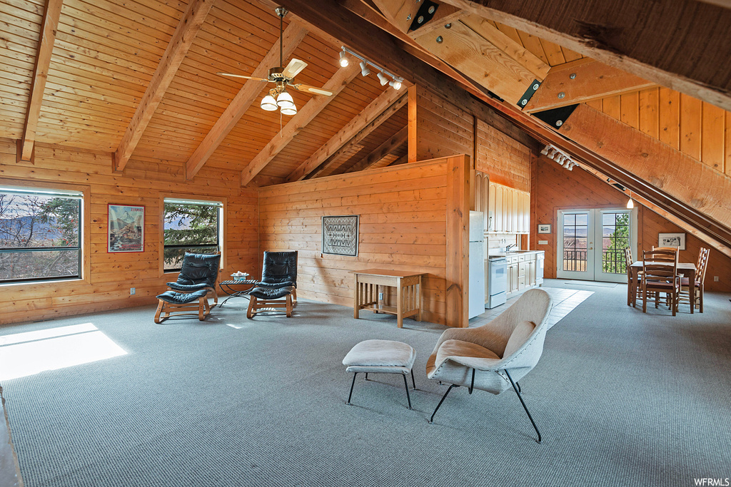Sitting room with light colored carpet, ceiling fan, wooden ceiling, and vaulted ceiling with beams
