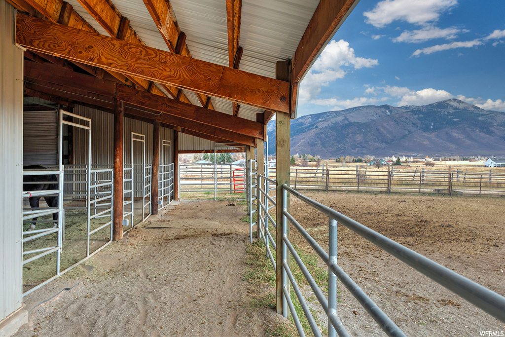View of horse barn with a rural view and a mountain view