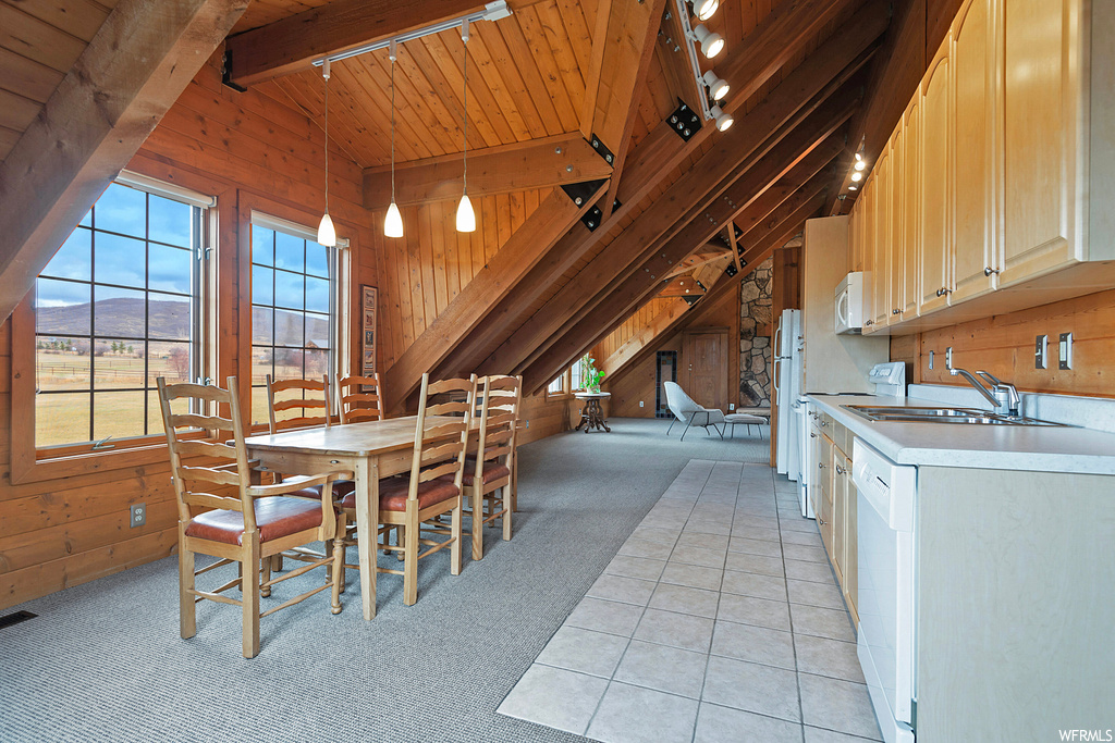 Carpeted dining space featuring sink, wood ceiling, beam ceiling, rail lighting, and wood walls