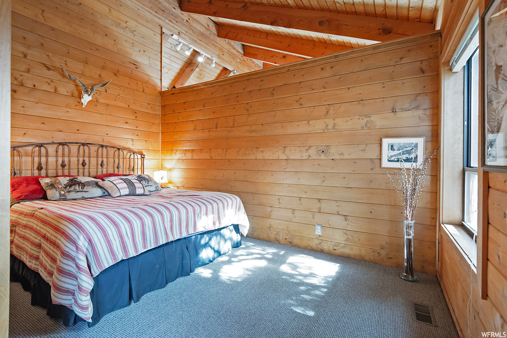 Bedroom with rail lighting, carpet floors, multiple windows, and vaulted ceiling with beams