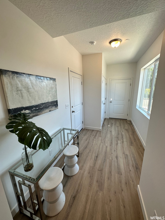 Hallway with light wood-type flooring and a textured ceiling