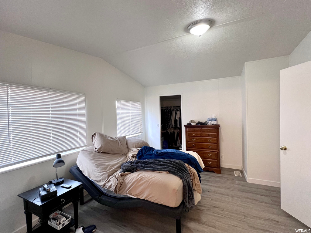 Bedroom featuring lofted ceiling and light hardwood / wood-style flooring