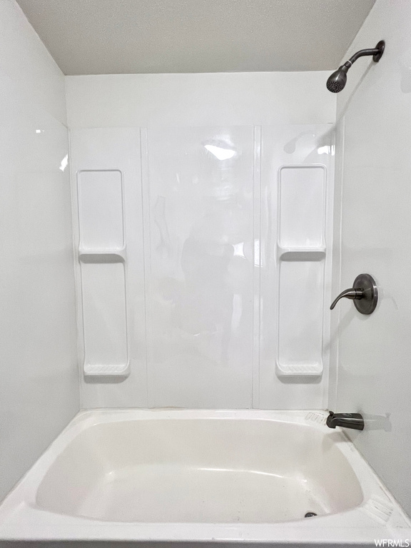 Bathroom with a textured ceiling and shower / tub combination