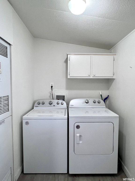 Clothes washing area with washer hookup, cabinets, a textured ceiling, washer and clothes dryer, and dark hardwood / wood-style floors