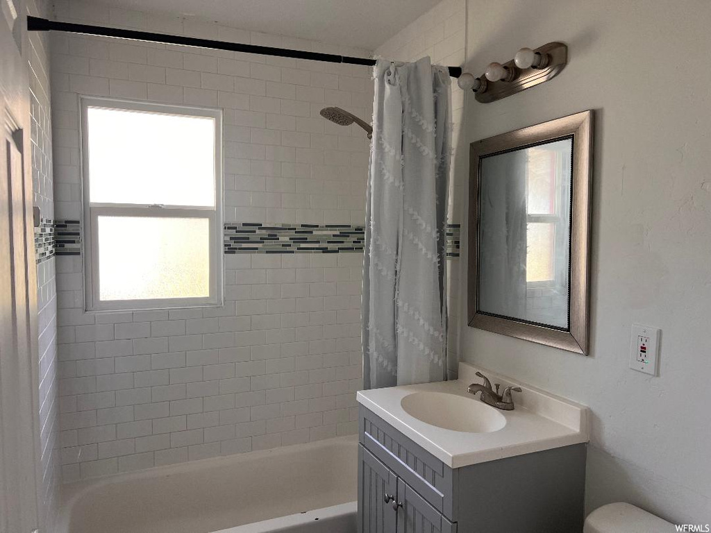 Bathroom with shower / tub combo, a wealth of natural light, and vanity