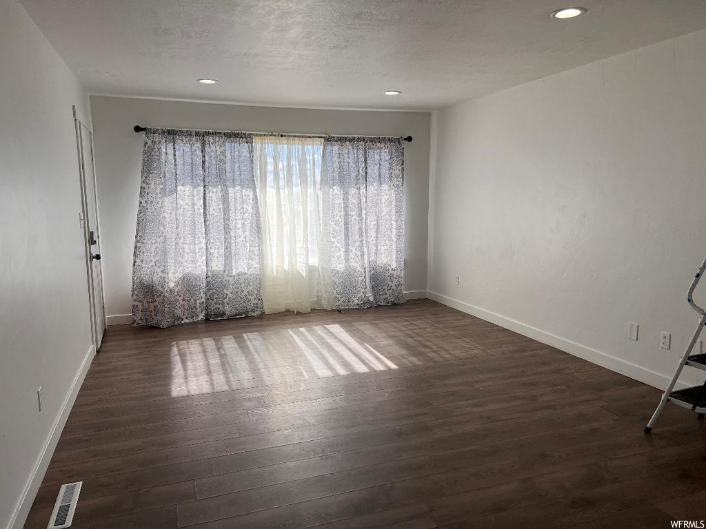Spare room with a textured ceiling and dark hardwood / wood-style flooring