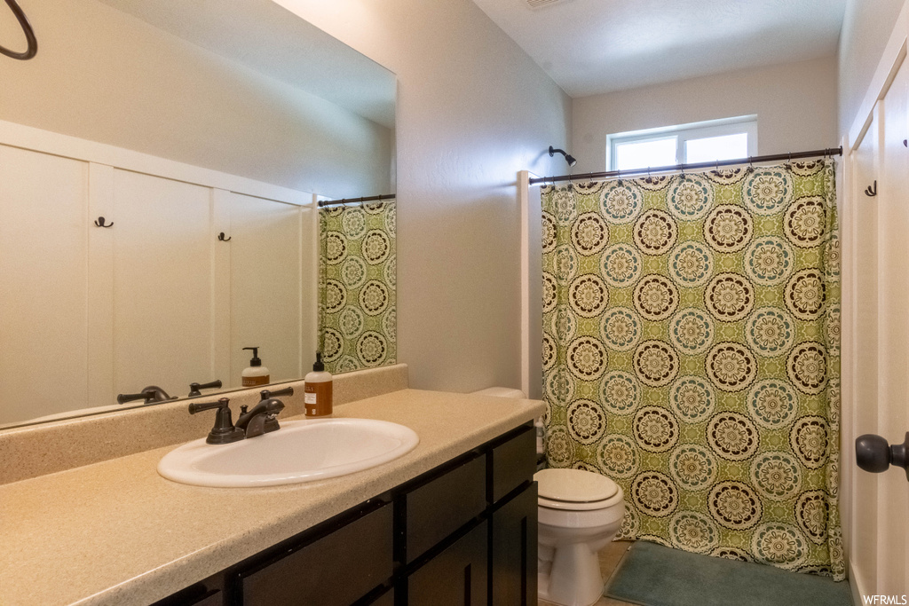 Full bathroom with toilet, shower / bath combination with curtain, and vanity with extensive cabinet space