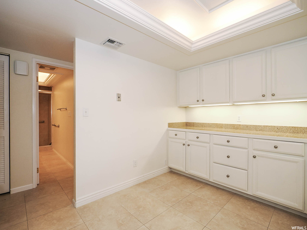 Kitchen featuring ornamental molding, white cabinets, and light tile floors