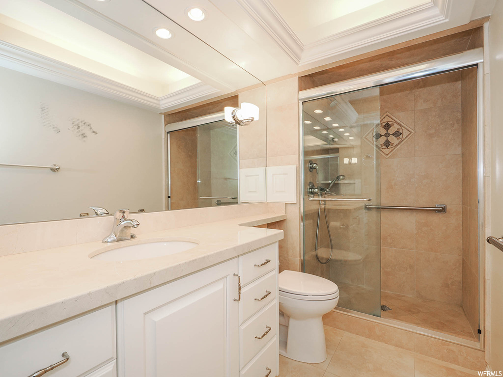 Bathroom with an enclosed shower, tile flooring, toilet, ornamental molding, and vanity with extensive cabinet space