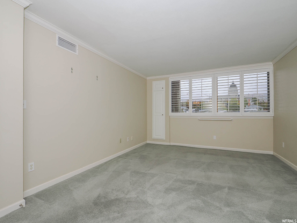 Unfurnished room with light colored carpet and crown molding