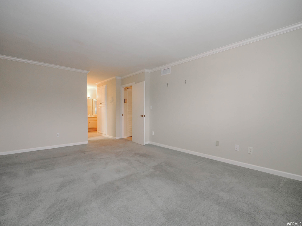 Empty room featuring light carpet and crown molding