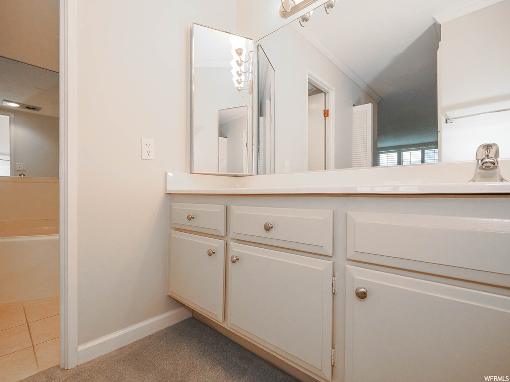 Bathroom featuring vanity, crown molding, tile flooring, and a bath